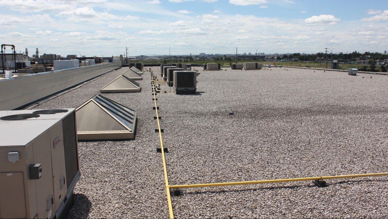 An expanse of ballasted flat roof running to the parapet, with skylights and a gas line along one edge.