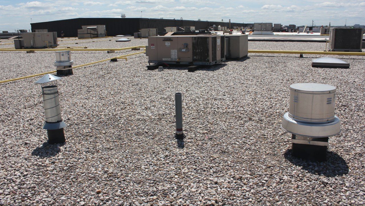 Roof vents and a rooftop unit on a ballasted commercial flat roof.